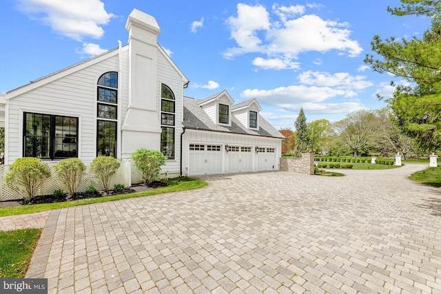 view of side of home featuring decorative driveway and an attached garage