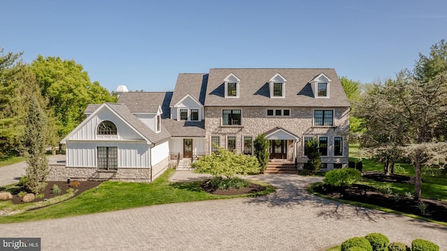 view of front facade featuring board and batten siding, stone siding, and a front lawn