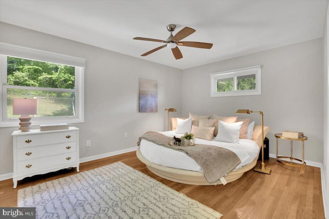 bedroom featuring baseboards, multiple windows, and wood finished floors