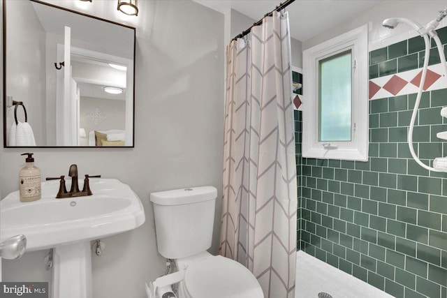 full bathroom featuring a sink, a tile shower, and toilet