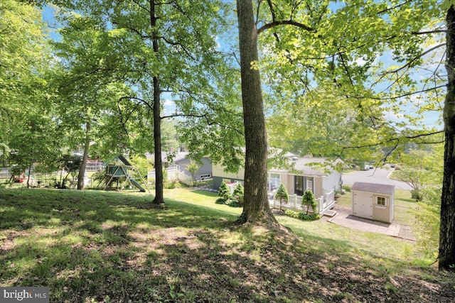 view of yard with an outdoor structure, a shed, and a playground