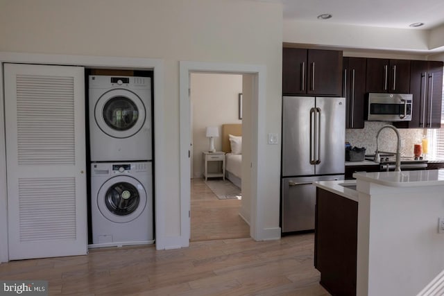 1421 Florida Ave NW Unit 5, Washington, DC 20009 - kitchen featuring decorative backsplash, stacked washer and dryer, light countertops, stainless steel appliances, and light wood-style flooring
