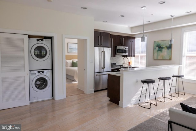 1421 Florida Ave NW Unit 5, Washington, DC 20009 - kitchen with a healthy amount of sunlight, a kitchen bar, dark brown cabinets, stacked washer and clothes dryer, and stainless steel appliances