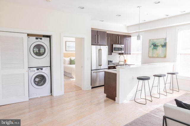 1421 Florida Ave NW Unit 5, Washington, DC 20009 - kitchen with stainless steel appliances, stacked washing machine and dryer, a kitchen bar, dark brown cabinetry, and light countertops