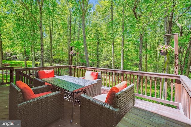 wooden deck featuring a view of trees and outdoor dining space