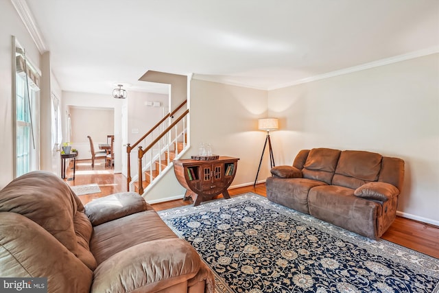 living room with crown molding, a notable chandelier, stairs, baseboards, and wood finished floors