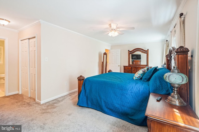 carpeted bedroom with baseboards, ornamental molding, ceiling fan, and a closet
