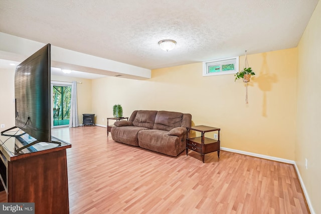 living area with a textured ceiling, baseboards, and light wood-style flooring
