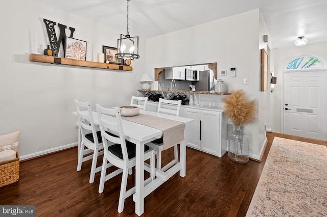 dining room with a chandelier, dark wood finished floors, and baseboards