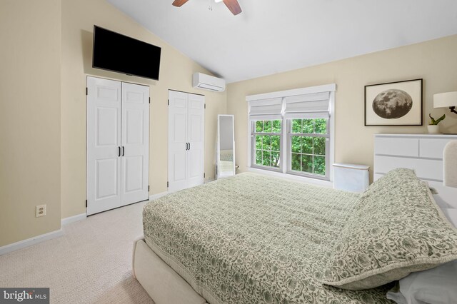 bedroom featuring an AC wall unit, multiple closets, light carpet, vaulted ceiling, and baseboards