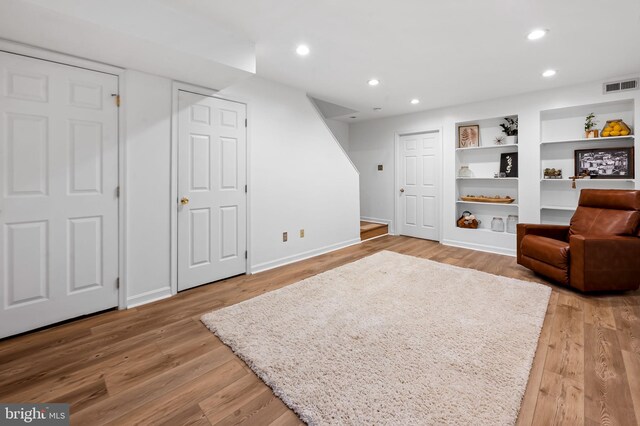 sitting room with baseboards, light wood finished floors, recessed lighting, and built in features