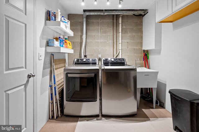 washroom with separate washer and dryer, concrete block wall, and cabinet space