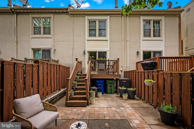 rear view of property featuring a patio, a fenced backyard, stucco siding, and a deck