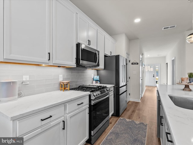 35040 Dundee St Unit 133, Frankford, DE 19945 - kitchen featuring white cabinetry, visible vents, light wood-type flooring, appliances with stainless steel finishes, and decorative backsplash