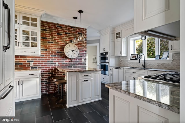 kitchen featuring a center island, dark tile patterned floors, white cabinetry, a sink, and stainless steel appliances