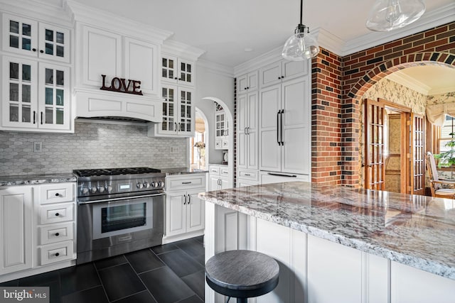 kitchen with decorative backsplash, white cabinetry, ornamental molding, and high end stove