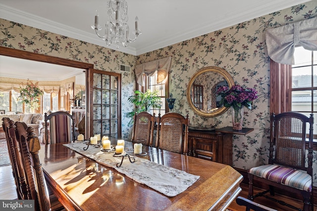 dining room featuring visible vents, ornamental molding, a notable chandelier, and wallpapered walls