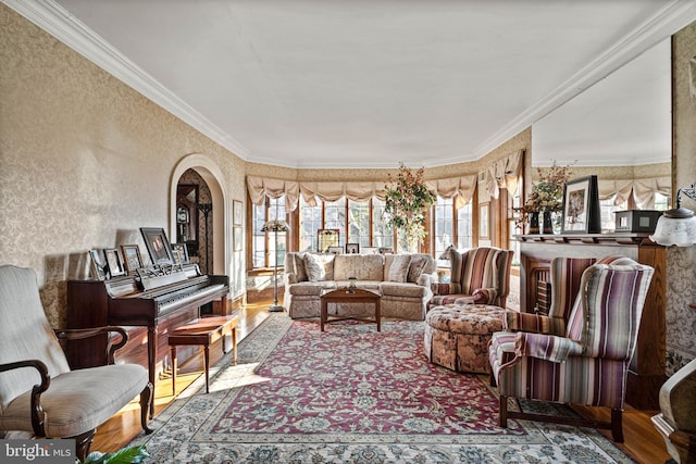 living room featuring arched walkways, ornamental molding, wallpapered walls, and wood finished floors