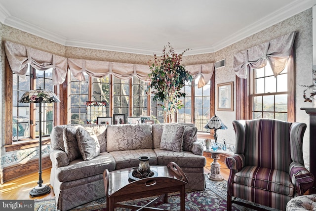 living area featuring visible vents, crown molding, wood finished floors, and a healthy amount of sunlight