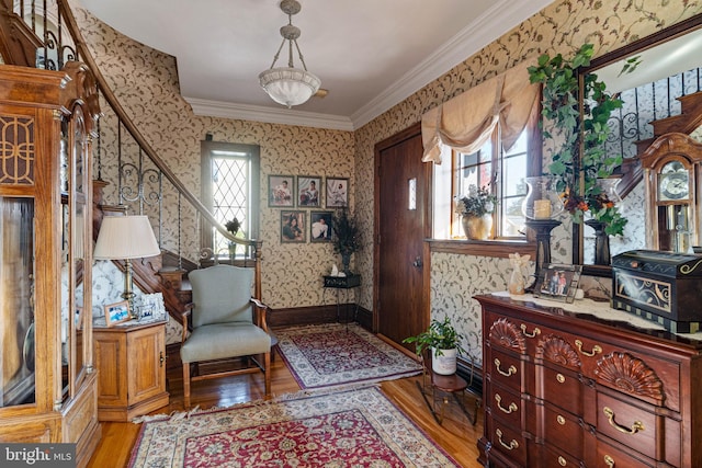 living area featuring light wood-type flooring, ornamental molding, stairs, and wallpapered walls
