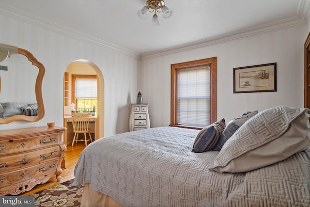 bedroom featuring visible vents, ornamental molding, wood finished floors, ensuite bathroom, and arched walkways