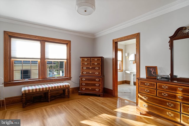 bedroom with baseboards, ornamental molding, light wood-style flooring, and connected bathroom