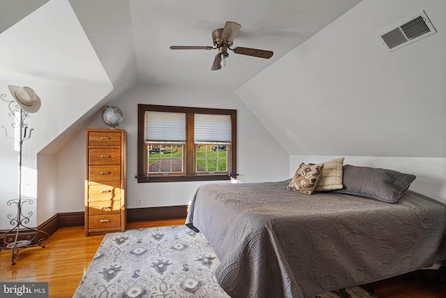 bedroom with light wood-style floors, a ceiling fan, vaulted ceiling, and visible vents