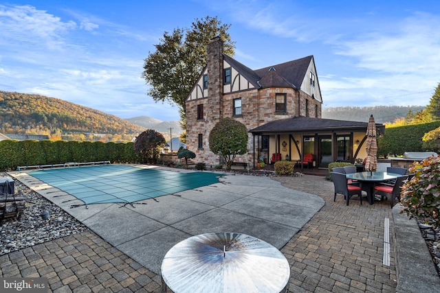view of swimming pool featuring a fenced in pool, outdoor dining area, a patio area, and a mountain view