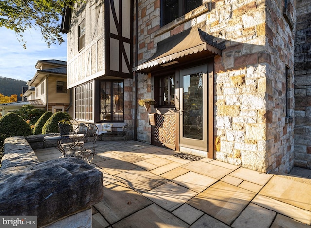 view of exterior entry with a patio area and stone siding