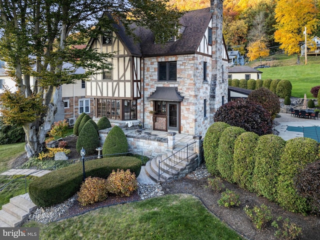 exterior space featuring a patio, stone siding, and a front lawn
