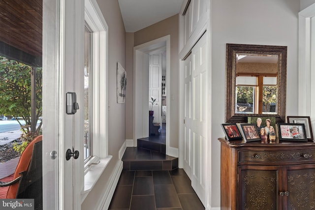 hallway featuring dark tile patterned floors and baseboards