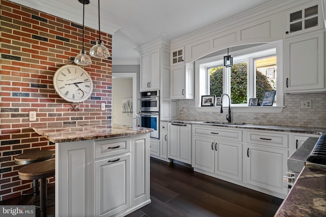 kitchen with crown molding, a sink, stainless steel double oven, and tasteful backsplash