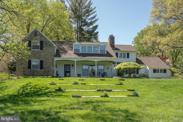 back of property with board and batten siding, a lawn, a chimney, and a porch