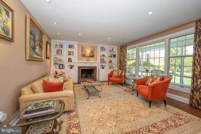 living area featuring a fireplace, built in features, recessed lighting, baseboards, and wood finished floors