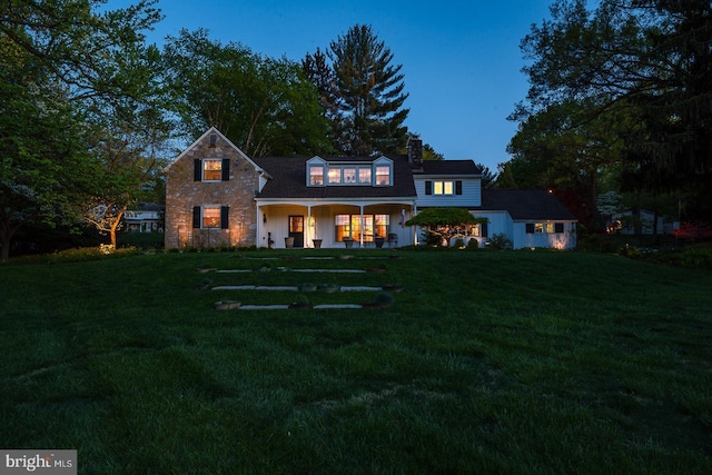 view of front of house with a chimney, covered porch, and a front yard