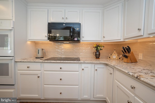 kitchen featuring light stone counters, white cabinets, backsplash, and black appliances