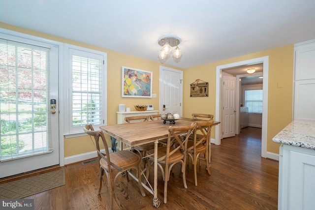 dining space featuring baseboards, dark wood finished floors, a healthy amount of sunlight, and visible vents