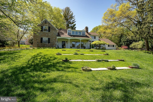 back of property featuring a lawn, covered porch, and a chimney