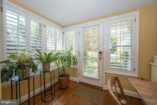 doorway featuring baseboards and wood finished floors