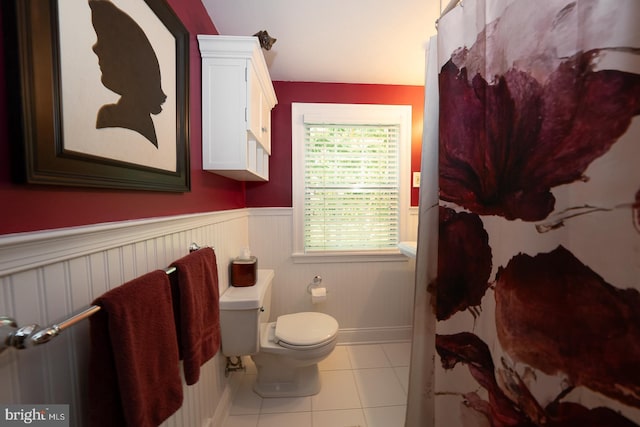 full bath with tile patterned floors, a wainscoted wall, toilet, and a shower with curtain