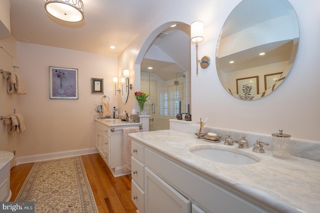 full bath featuring a sink, a shower stall, wood finished floors, and visible vents