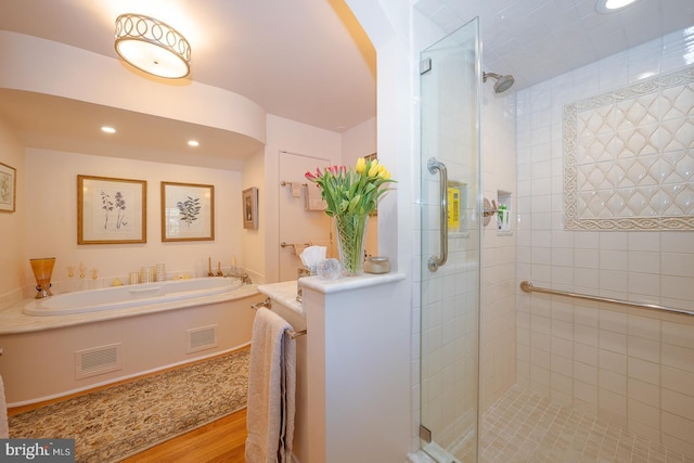 bathroom featuring visible vents, a shower stall, wood finished floors, and a bath
