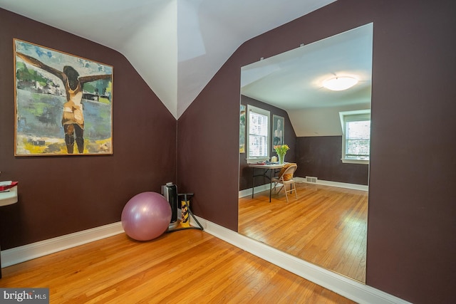 workout room featuring baseboards, wood finished floors, and vaulted ceiling