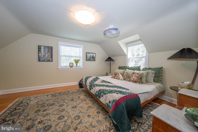 bedroom with baseboards, wood finished floors, and vaulted ceiling