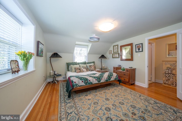 bedroom with baseboards, wood finished floors, and vaulted ceiling