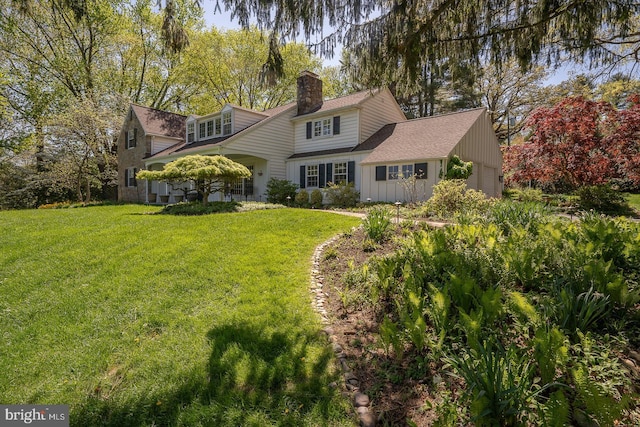 view of front of home featuring an attached garage, a shingled roof, a front yard, and a chimney