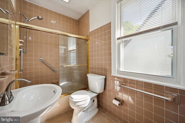 full bathroom with a sink, toilet, tile patterned floors, tile walls, and tiled shower