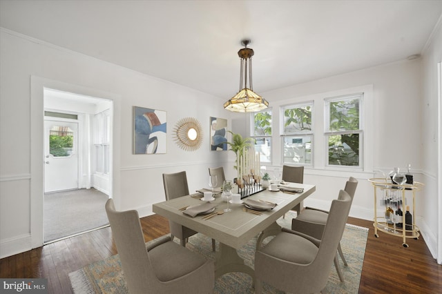 dining space with dark wood-type flooring, baseboards, and crown molding