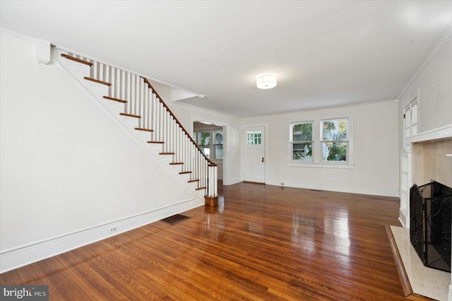 unfurnished living room featuring visible vents, a fireplace with flush hearth, wood finished floors, and stairway