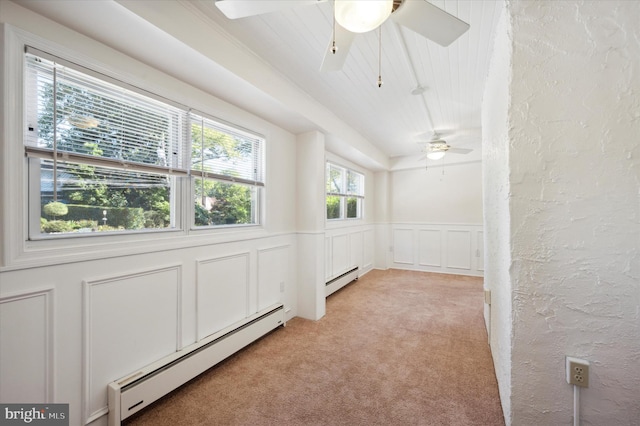 spare room with light colored carpet, a ceiling fan, a decorative wall, and a baseboard heating unit